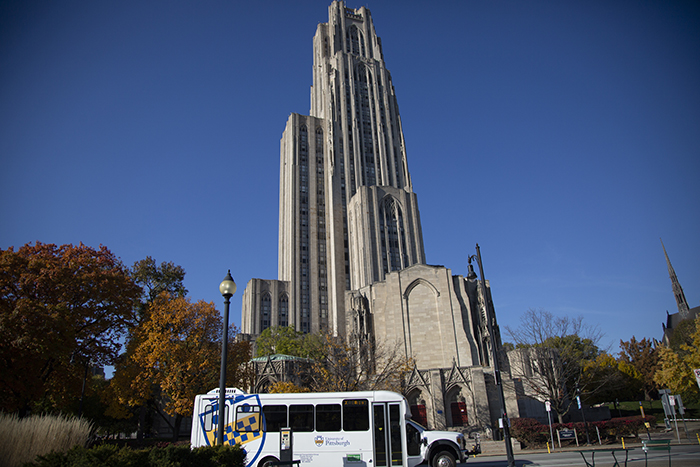 a campus shuttle parked in front of the cathedral of learning. 