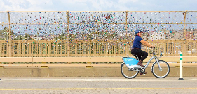 Healthy Ride user biking across a bridge. 