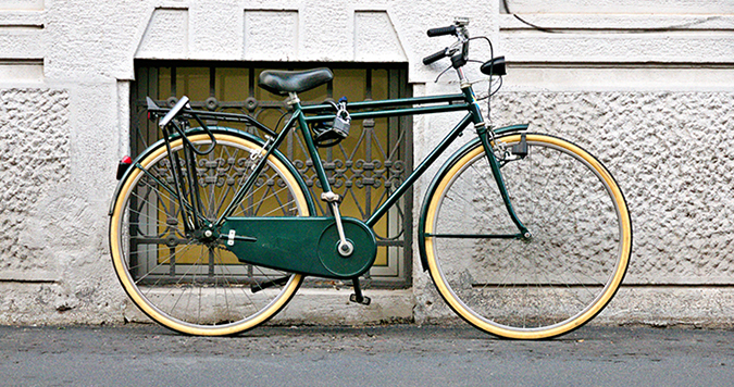 Green and yellow bike leaning against a wall. 
