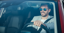 man wearing sunglasses, driving a car