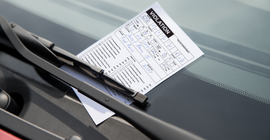 Parking ticket positioned under windshield wiper blade.